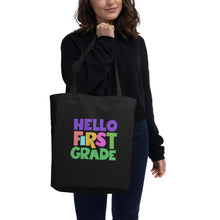 Load image into Gallery viewer, HELLO FIRST GRADE Eco Tote Bag for Teachers | Black | 16&quot; x 14.5&quot; | Front View Lifestyle Photo | Shop The Wishful Fish
